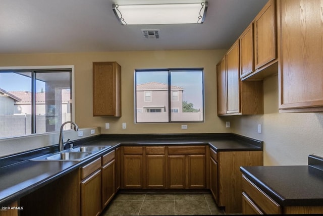 kitchen with dark countertops, visible vents, brown cabinets, and a sink