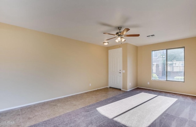 empty room with ceiling fan, carpet, visible vents, and baseboards