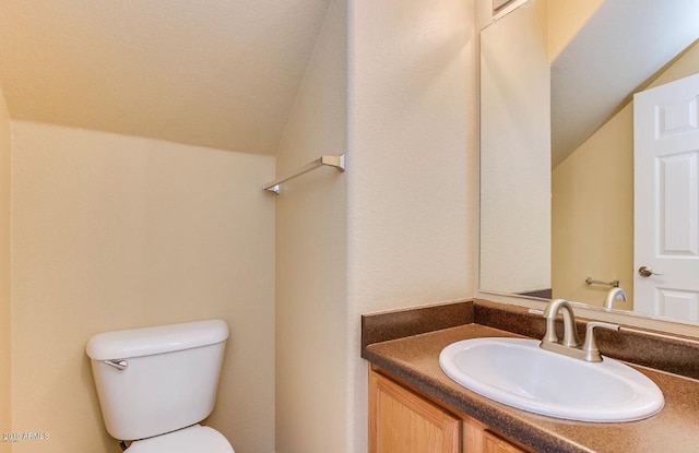 bathroom with lofted ceiling, toilet, and vanity