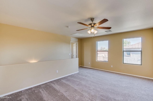 carpeted spare room with visible vents, ceiling fan, and baseboards