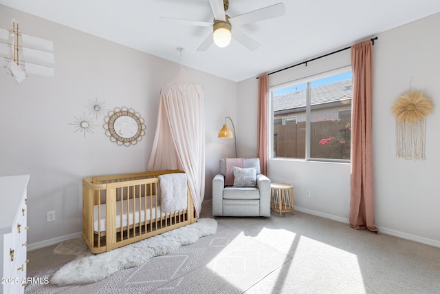 bedroom featuring light carpet, a crib, and ceiling fan