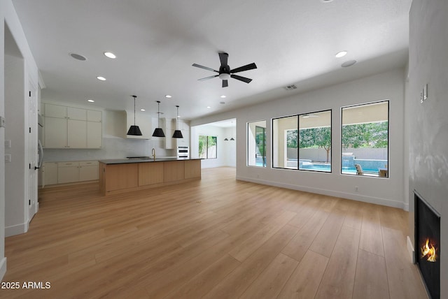 2859 E Los Altos Rd, Gilbert, AZ 85297 - unfurnished living room featuring recessed lighting, light wood-type flooring, ceiling fan, and a warm lit fireplace