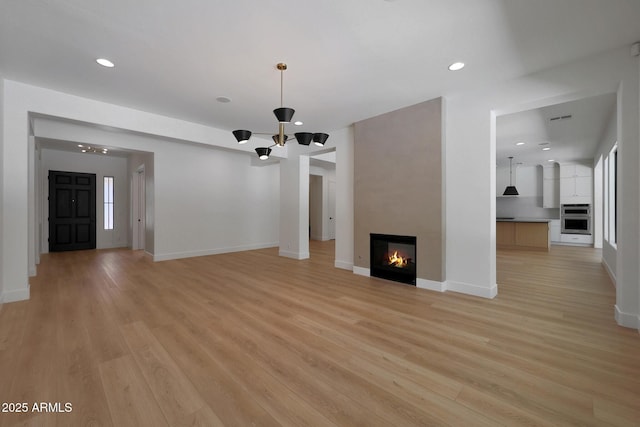 2859 E Los Altos Rd, Gilbert, AZ 85297 - unfurnished living room with a chandelier, recessed lighting, light wood-style floors, and a large fireplace
