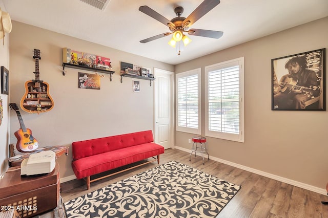 living area featuring visible vents, baseboards, a ceiling fan, and wood finished floors