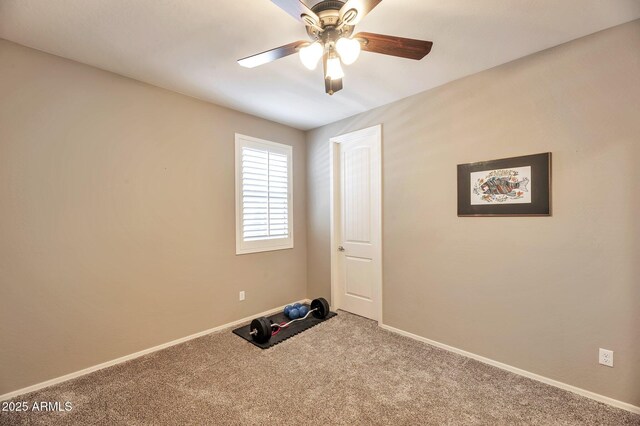 carpeted empty room featuring baseboards and a ceiling fan