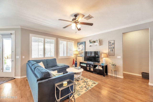 living room featuring light wood finished floors, crown molding, ceiling fan, and baseboards