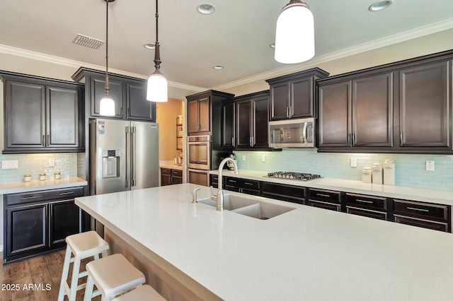 kitchen featuring visible vents, a breakfast bar, appliances with stainless steel finishes, a sink, and hanging light fixtures