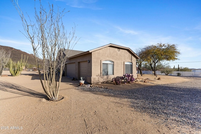 view of front of house featuring driveway, an attached garage, a mountain view, and stucco siding