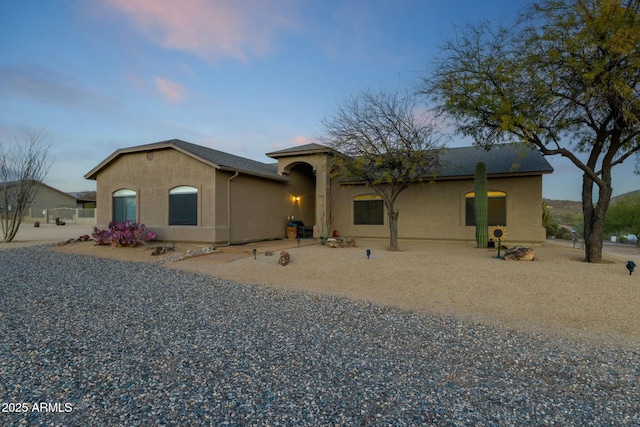 mediterranean / spanish home featuring gravel driveway and stucco siding