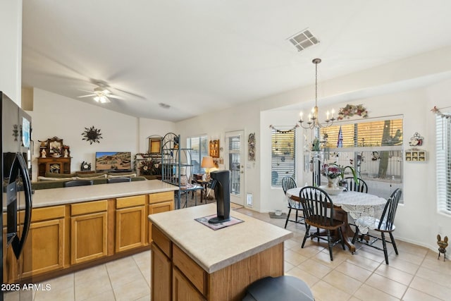 kitchen featuring a kitchen island, visible vents, light countertops, black fridge, and decorative light fixtures