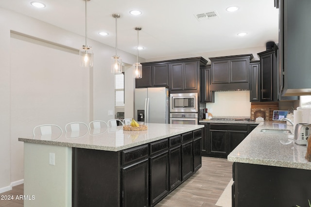 kitchen featuring pendant lighting, stainless steel appliances, a center island, and light hardwood / wood-style flooring