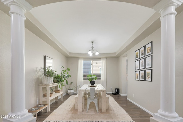 dining area featuring dark wood-type flooring, a raised ceiling, and an inviting chandelier