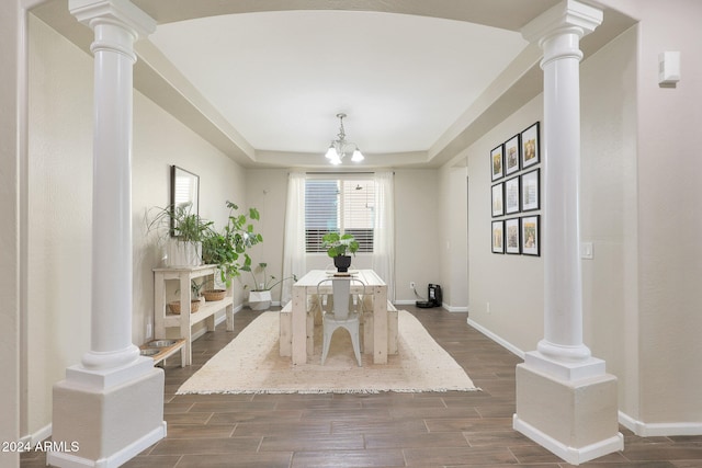 dining area with dark wood-type flooring, a tray ceiling, and an inviting chandelier