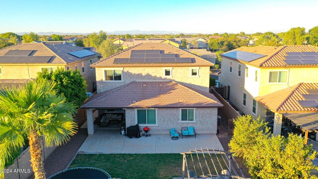 back of house with a patio, solar panels, and a lawn