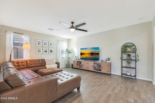 living room with ceiling fan, plenty of natural light, and light wood-type flooring