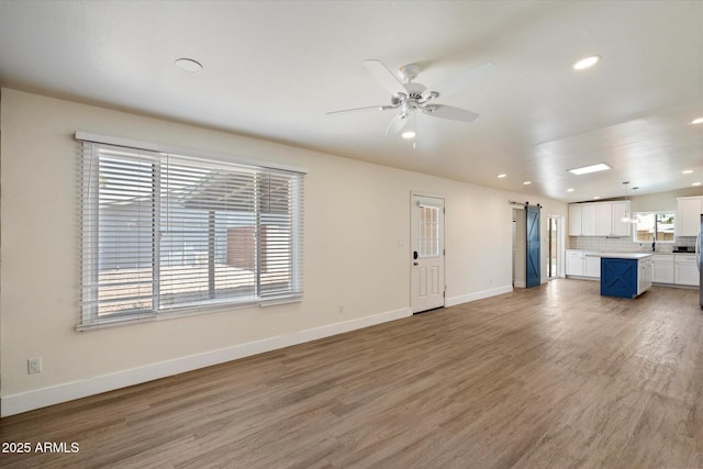1939 E Alameda Dr, Tempe, AZ 85282 - unfurnished living room with a barn door, recessed lighting, light wood-style floors, a ceiling fan, and baseboards