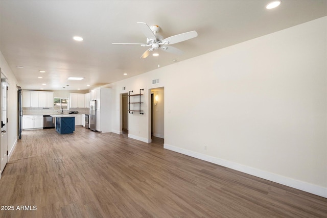 1939 E Alameda Dr, Tempe, AZ 85282 - unfurnished living room featuring wood finished floors, recessed lighting, baseboards, a ceiling fan, and a sink