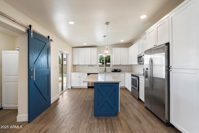 1939 E Alameda Dr, Tempe, AZ 85282 - kitchen featuring stainless steel appliances, backsplash, light countertops, wood finished floors, and a kitchen island