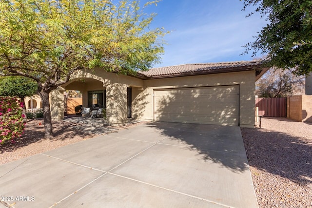 view of front of property featuring a tiled roof, concrete driveway, an attached garage, and stucco siding