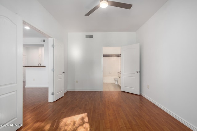 unfurnished bedroom featuring ceiling fan, dark wood-type flooring, and connected bathroom