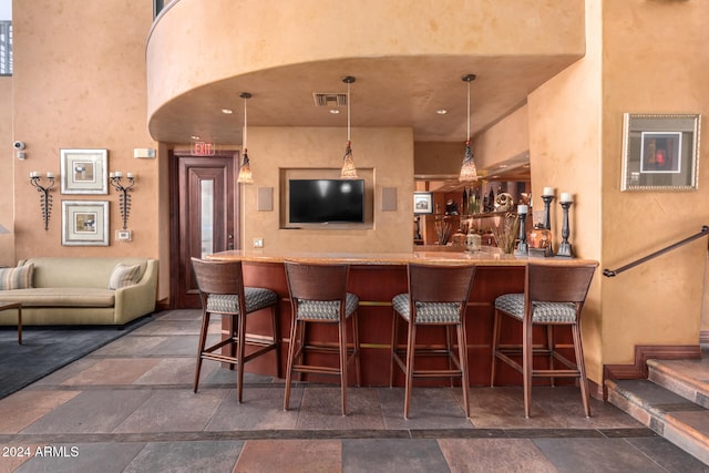 bar featuring pendant lighting and a towering ceiling