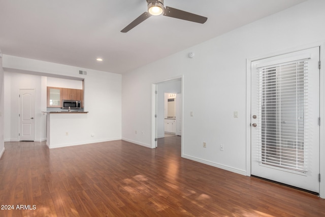 unfurnished living room featuring ceiling fan and dark hardwood / wood-style floors