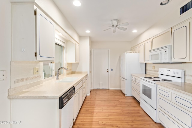 kitchen with sink, white cabinetry, tasteful backsplash, white appliances, and light hardwood / wood-style floors