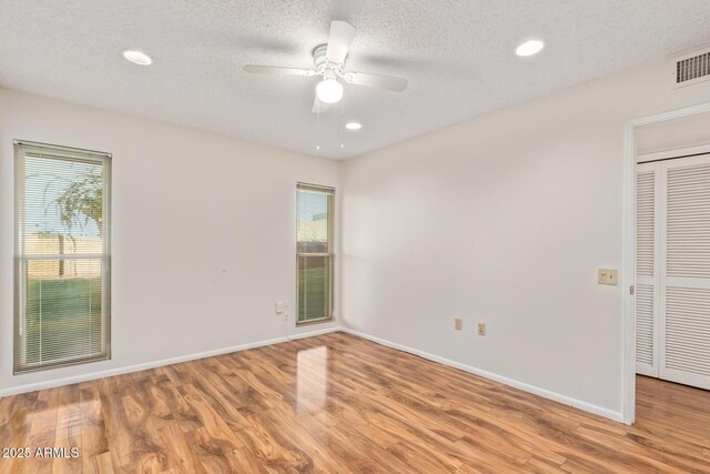 unfurnished room with light wood-type flooring, a textured ceiling, and ceiling fan