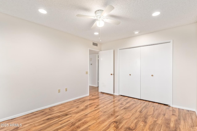 unfurnished bedroom with a closet, ceiling fan, a textured ceiling, and light wood-type flooring