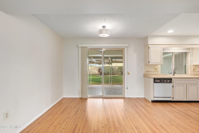 kitchen with a textured ceiling, sink, light hardwood / wood-style flooring, and dishwasher