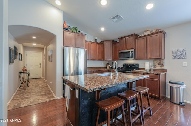 kitchen featuring vaulted ceiling, a breakfast bar area, dark hardwood / wood-style flooring, a kitchen island with sink, and electric range