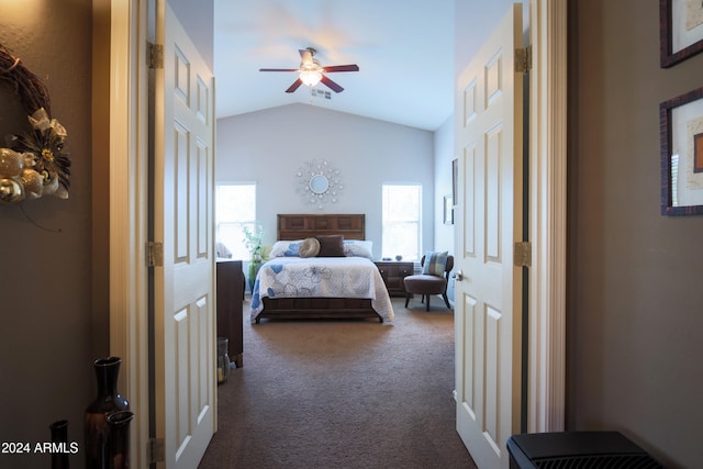 bedroom with dark colored carpet, vaulted ceiling, multiple windows, and ceiling fan