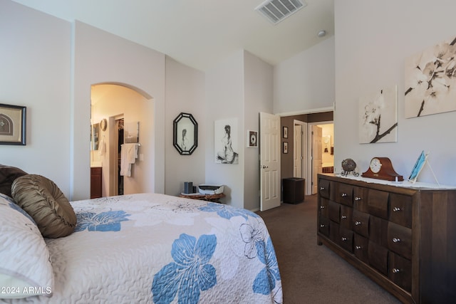 bedroom featuring a high ceiling, ensuite bath, and dark carpet