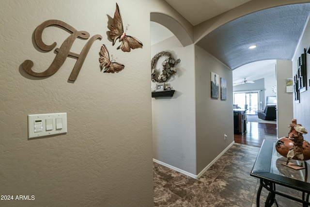 hall featuring a textured ceiling and vaulted ceiling