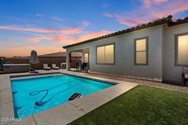 pool at dusk with a patio area