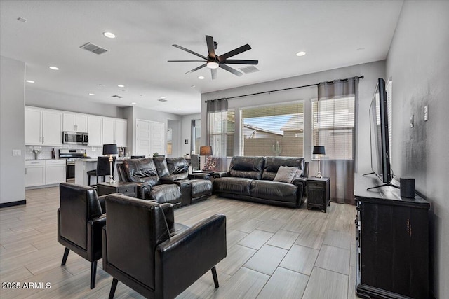 living room featuring a ceiling fan, recessed lighting, and light wood finished floors