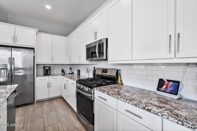 kitchen with appliances with stainless steel finishes, white cabinetry, decorative backsplash, recessed lighting, and light stone counters