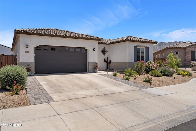 mediterranean / spanish-style house with concrete driveway, an attached garage, a tile roof, and stucco siding