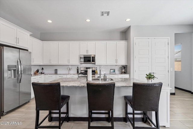kitchen with appliances with stainless steel finishes, backsplash, white cabinetry, and recessed lighting