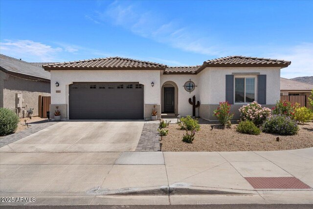 mediterranean / spanish-style home with an attached garage, concrete driveway, stucco siding, and a tiled roof