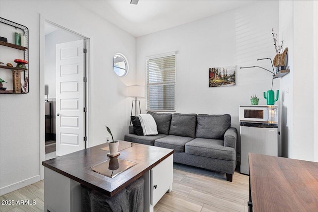 living area featuring baseboards and light wood-style flooring