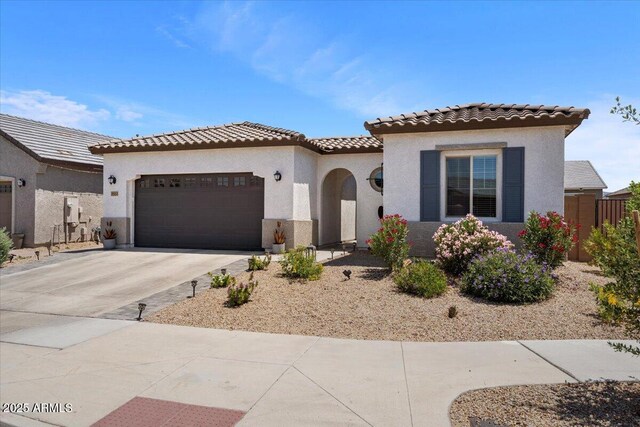 mediterranean / spanish-style house featuring an attached garage, driveway, stucco siding, and a tile roof