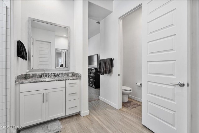 full bathroom with toilet, vanity, baseboards, and wood finished floors
