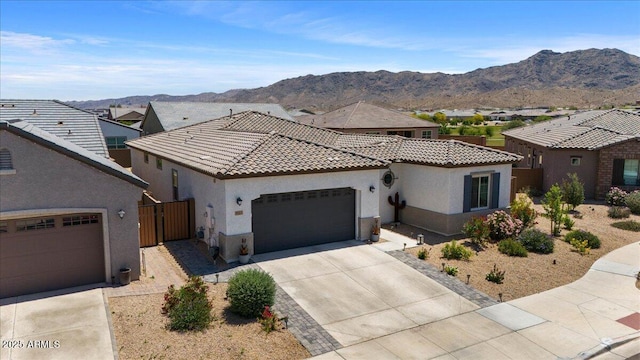 view of front of property featuring stucco siding, driveway, a garage, a tile roof, and a mountain view