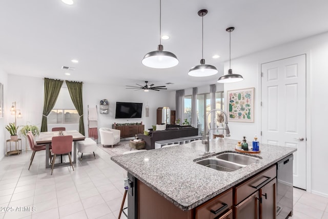 kitchen with a ceiling fan, a kitchen island with sink, a sink, pendant lighting, and stainless steel dishwasher