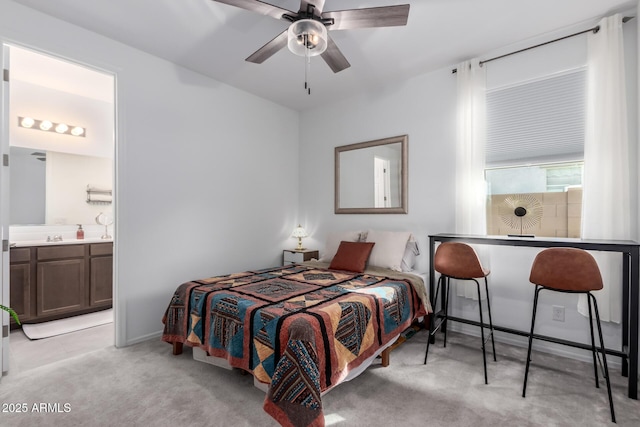 bedroom with baseboards, light colored carpet, ensuite bath, and a ceiling fan