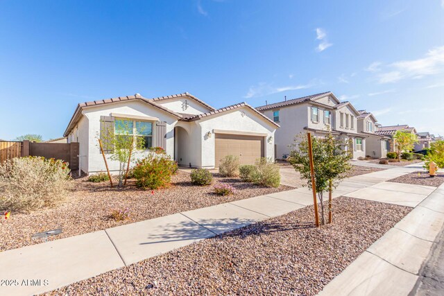 view of front of house with stucco siding, driveway, a tile roof, fence, and an attached garage