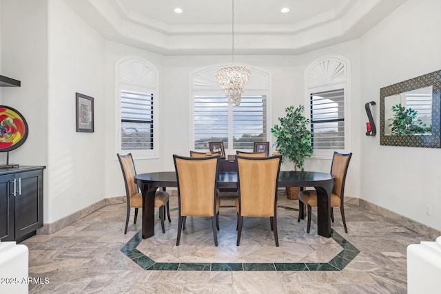 dining space with a tray ceiling and a notable chandelier