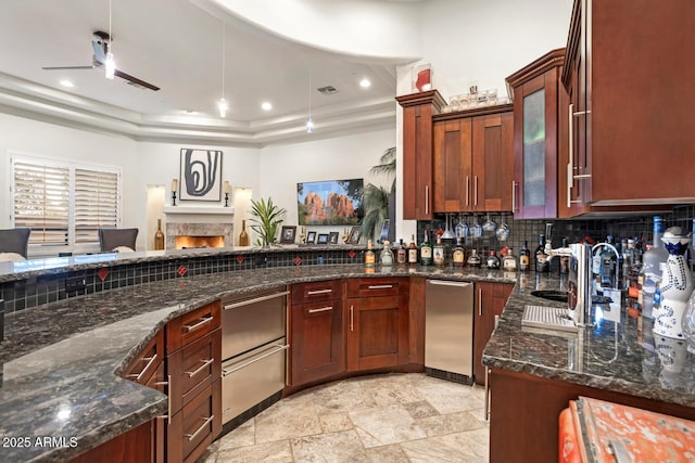 kitchen featuring dark stone counters, sink, and a tray ceiling