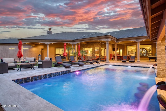 pool at dusk with outdoor lounge area, pool water feature, and a patio